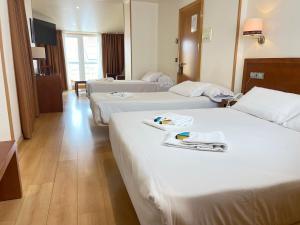 菲尼斯特雷Hotel Spa Playa Langosteira by Adeloló的酒店客房,配有三张床和毛巾