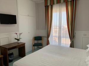 伊斯基亚康特酒店的一间卧室配有一张床、一张书桌和一个窗户。