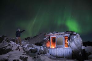 Melbu伯希德斯图阿度假屋的站在小屋旁的北极光下的人