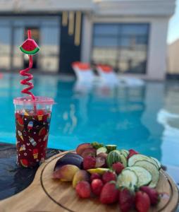 伊尔比德Tixos Farm的一杯水果和一杯饮料,在游泳池旁边