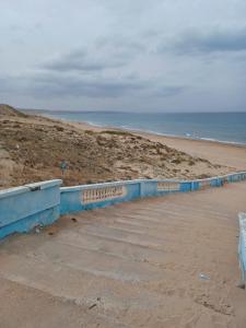 MostaganemMAISON DE VACANCE的蓝色挡墙和海洋的海滩