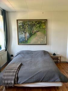 阿森斯Bøgebjerggårds Gårdbutik的卧室内的一张床铺,墙上有绘画作品