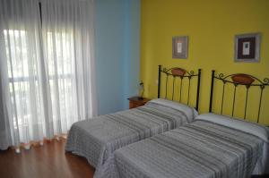 萨莫拉Hotel Puente de Piedra的黄色墙壁客房中的两张单人床