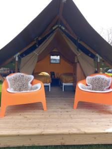 蒂尔Safari Lodge Aan de Linge的帐篷内的两张床和橙色椅子