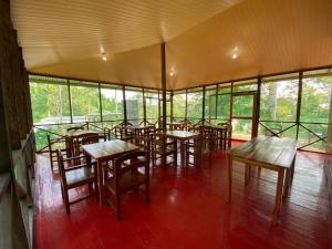 莱蒂西亚Amazon Açaí Lodge的餐厅设有木桌、椅子和窗户。