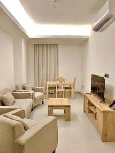 Ḩayl Āl ‘UmayrIveria Hotel Apartments的带沙发、电视和桌子的客厅