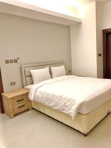 Ḩayl Āl ‘UmayrIveria Hotel Apartments的卧室配有一张白色的大床和床头柜。
