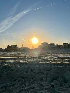 欧申格罗夫Beachliner Hotel的日落在海滩上,阳光在海滩上