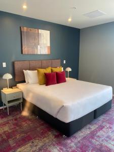 奥克兰La Quinta by Wyndham Parnell Auckland的一间卧室配有一张大床,提供红色和黄色枕头