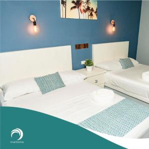 Monte GordoHotel Bungalows Marbella Costa Esmeralda的蓝色墙壁客房的两张床