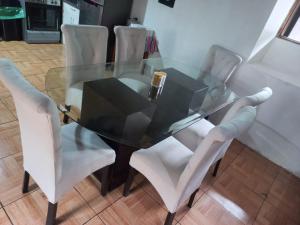 库斯科SajaHome的玻璃餐桌周围摆放着白色椅子