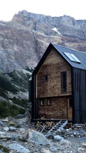 厄尔查尔坦Puesto Cagliero - Refugio de montaña的山间小木屋,背景为山脉