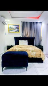拉各斯60B Adetoun Adelaja 4Bedroom的一间卧室配有一张大床和蓝色的搁脚凳