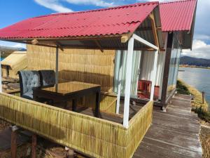 普诺Coila Titicaca lodge的一座红色屋顶的房子,甲板上设有一张桌子
