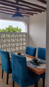 迪亚尼海滩Bedroom Diani Beach的一张带蓝色椅子的餐桌和窗户