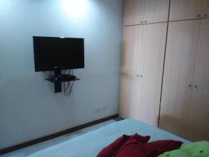 拉瓜伊拉Acogedor apartamento con piscina - Bleu Marine Suites的一间卧室设有一张带平面电视的床。