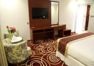 吉达Wow Hotel Jeddah的酒店客房配有一张床、一张书桌和一台电视。