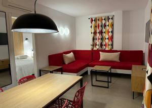 圣安东尼奥Aparthotel Boutique Poniente Playa的客厅配有红色的沙发和桌子