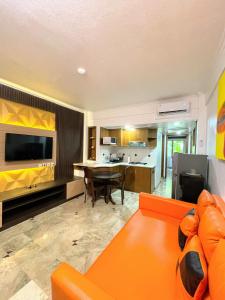塞米亚克Suite Hotel Apartment Legian by RCP的一间带橙色沙发的客厅和一间厨房
