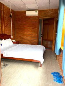 Tân PhúDu Nam Riverside Tour Trọn Gói的卧室配有白色的床和砖墙