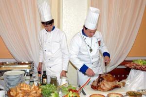 皮塞克白玫瑰大酒店的两位厨师在餐桌上准备火鸡,配上食物