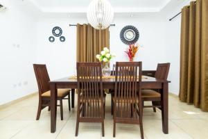 阿克拉Stay Play Away Residences - Luxury 4 bed, Airport Residential, Accra的一间带木桌和椅子的用餐室