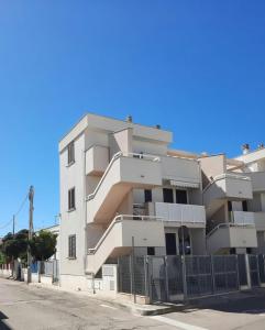切萨雷奥港La Vela Apartaments - Porto Cesareo的白色的公寓楼,前面设有围栏