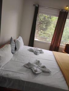 马迪凯里Katakeri Deluxe Holiday Homes的一张白色的床,上面有两双鞋,有窗户