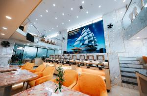 芽庄Napoleon Nha Trang Hotel的一间设有橙色椅子的餐厅,墙上有一艘船