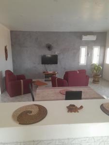 索蒙La doré du Sénégal的客厅配有红色椅子和平面电视
