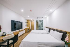 岑山Hệ thống Khách Sạn Sen Biển Sầm Sơn的一间酒店客房,设有两张床和电视