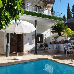 格拉纳达Suite Comares的一座带遮阳伞和游泳池的房子