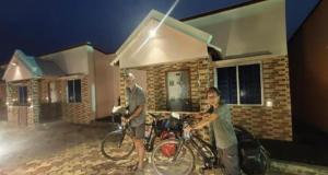 曼达莫尼Bongtel Beach Resort Mandarmani的两个人站在房子前面,骑着自行车