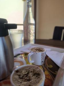科利希尔斯Kanna Garden by Bodhi Bungalows的桌子上放两杯咖啡,放一瓶