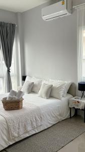 奈扬海滩House near the beach的一张白色的床,上面有白色的枕头和篮子