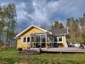 EkängGula Stugan Rönnäs Skogsväg的一个小黄色房子,设有大甲板