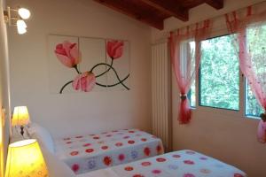 PerinaldoIl Rifugio Di Artemide AGRITURISMO的一间卧室设有两张床,墙上设有鲜花窗户。