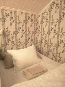 法伦Kopparstugans Bed & Breakfast的一张带白色枕头和花卉壁纸的床