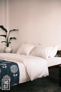 阿姆波尔This is it Beachfront - Rooms, Cafe & Events的一张带白色床单和盆栽的床