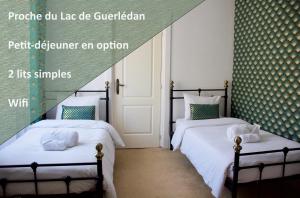 CaurelValfrescos - Lac de Guerlédan的卧室设有两张单人床,配有绿色壁纸