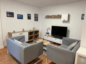 卢安科apartamento luanco playa的客厅配有2把椅子和平面电视