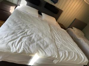 桑讷菲尤尔Leilighet i kjelleren nær Sandefjord Torp的一张带白色床单和枕头的未铺好的床