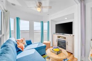 弗吉尼亚海滩Sea La Vie Beach Cottage的客厅配有蓝色的沙发和电视