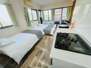 东京Ueno Iriya hostel的一间设有三张床和一台电视的房间