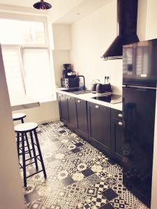 杜埃Le vintage 100 mètres de la gare parking gratuit的厨房配有黑色橱柜和瓷砖地板。
