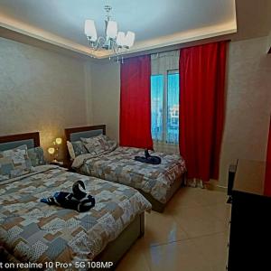 沙姆沙伊赫Sharm Hills Hotel的配有红色窗帘的客房内的两张床