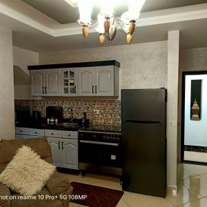 沙姆沙伊赫Sharm Hills Hotel的厨房配有黑冰箱和白色橱柜。