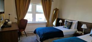 邓法纳希Arnolds Hotel的酒店客房设有两张床、一张书桌和一个窗户。