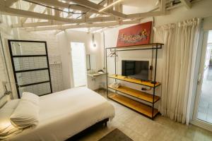 圣克鲁斯Cosmopolitano Hotel Boutique的卧室配有白色的床和电视。