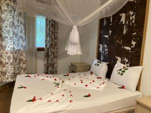 南威PASA LODGE ZANZIBAR的一间卧室配有一张白色的床铺,上面有红玫瑰